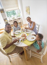 Mixed race family smiling at dining room table