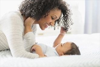 Mixed race mother holding baby on bed