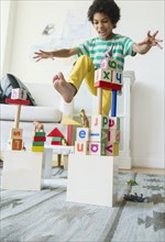 Mixed race boy wrecking wooden block city in living room