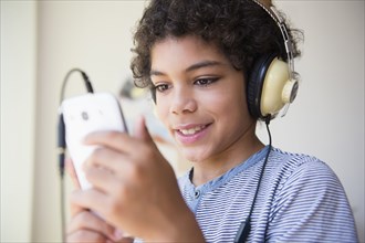 Mixed race boy listening to headphones and cell phone
