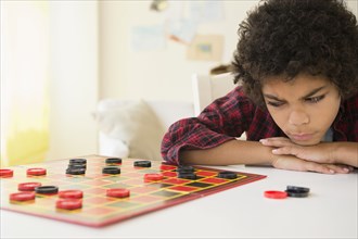 Angry mixed race boy losing game of checkers