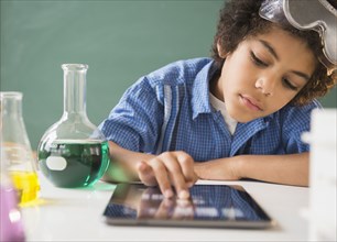 Mixed race boy using digital tablet in classroom science lab