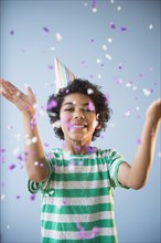 Mixed race boy throwing confetti at party