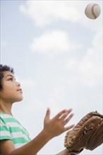 Mixed race boy throwing baseball outdoors