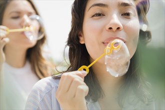 Hispanic women blowing bubbles outdoors