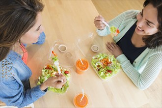 Hispanic women eating salad together at table