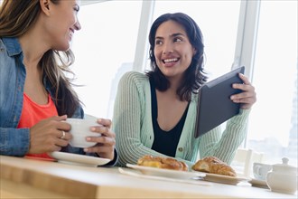 Hispanic women using digital tablet at breakfast