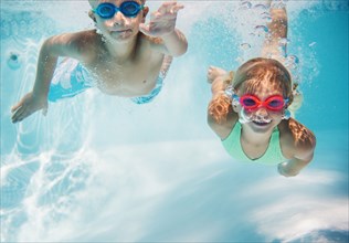 Caucasian children swimming underwater in pool