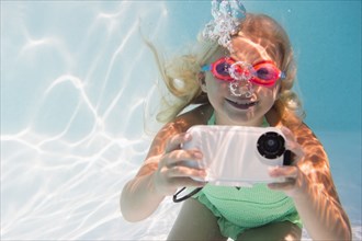 Caucasian girl taking photograph underwater in pool
