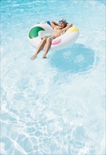 Caucasian boy floating in inflatable ring in swimming pool
