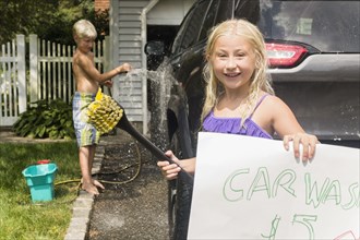 Caucasian children having car wash in driveway