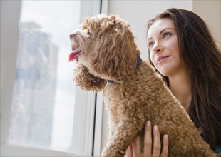 Caucasian woman looking out window with pet dog