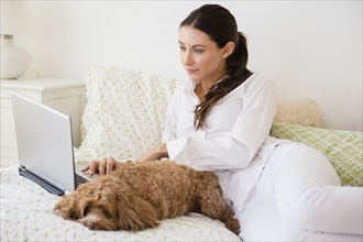 Caucasian woman using laptop with pet dog