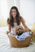 Caucasian woman carrying dog in basket of laundry