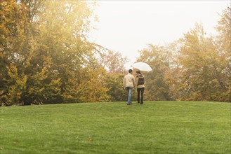 Couple walking with umbrella in park