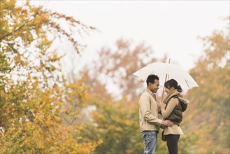 Couple standing with umbrella in park