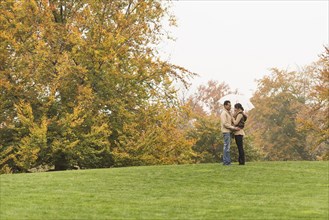 Couple standing with umbrella in park