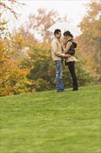 Couple standing with umbrella in park