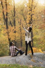 Woman cheering with arms outstretched near boyfriend in park