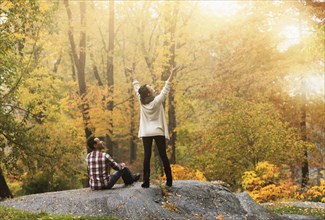 Woman cheering with arms outstretched near boyfriend in park