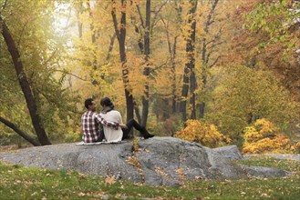 Asian couple hugging on rock in park