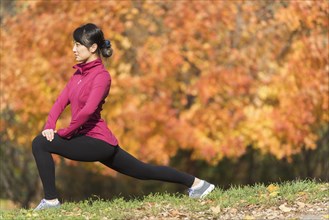 Asian runner stretching in park