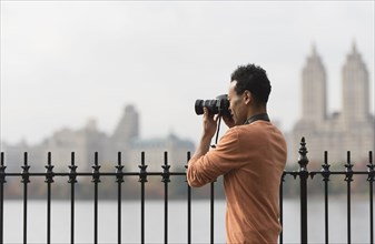 Mixed race man taking photograph on urban waterfront