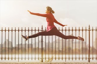 Asian woman leaping on waterfront path