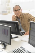 Korean businessman smiling at computer at office desk