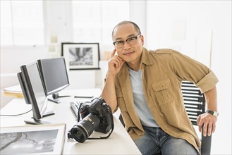 Korean photographer smiling at desk