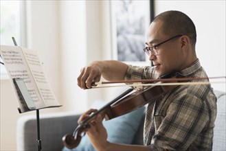 Korean musician playing violin in living room