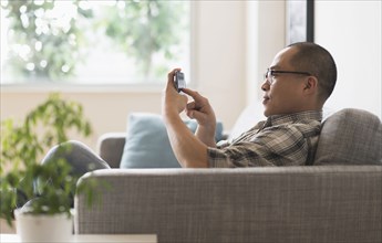 Korean man using cell phone on sofa