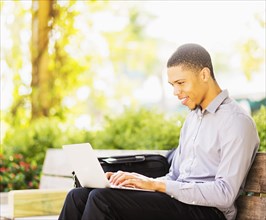 Black businessman using laptop outdoors