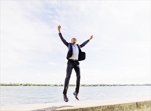 Black businessman jumping for joy outdoors