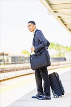 Black businessman waiting on train platform