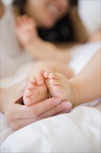 Close up of mixed race mother holding feet of baby