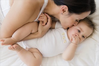 Overhead view of mixed race mother kissing baby on bed