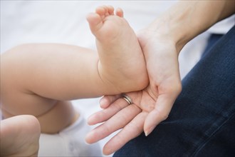 Close up of mixed race mother holding foot of baby