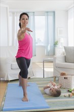 Mixed race mother practicing yoga and watching baby at home