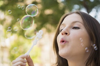 Close up of Caucasian woman blowing bubbles outdoors