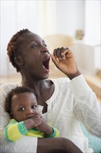 Yawning Black mother holding baby boy
