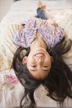 Smiling Vietnamese girl laying on bed