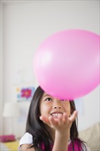 Smiling Vietnamese girl playing with pink balloon