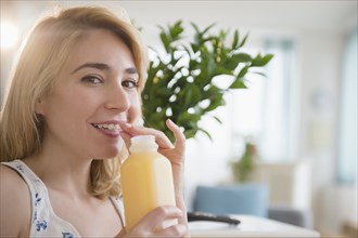 Caucasian woman drinking juice in living room