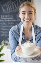 Caucasian barista serving coffee drink in cafe