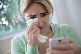 Crying Caucasian woman using cell phone
