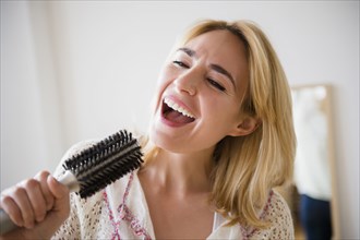 Caucasian woman singing into hairbrush