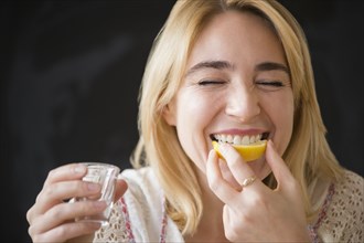Caucasian woman eating lemon slice with liquor shot