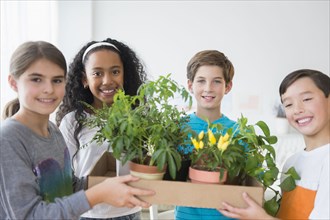 Smiling children holding potted plants