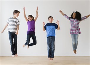 Smiling children jumping for joy in studio